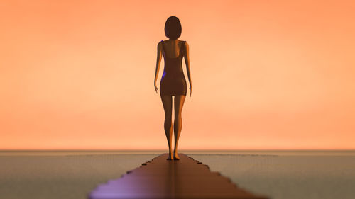 Rear view of man standing by sea against sky during sunset