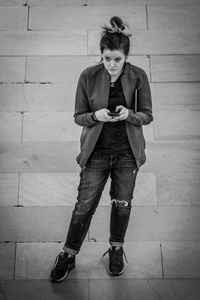 Portrait of young woman standing against wall