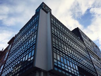 Low angle view of modern building against cloudy sky