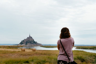 Rear view of woman looking at temple against sky