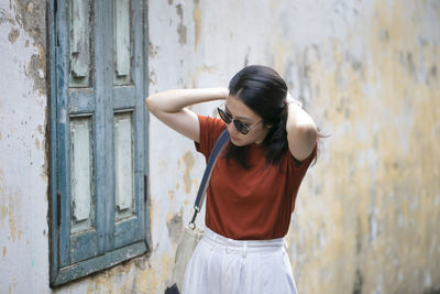 Woman in sunglasses standing against wall