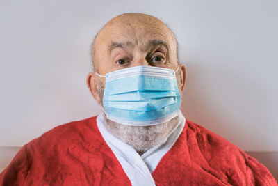 Elderly man wearing a face mask and santa claus suit