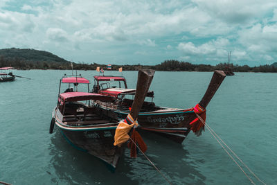 Fishing boats moored on sea against sky