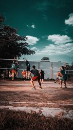 People playing soccer against sky