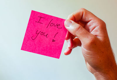 Hand holding a sticky note that says i love you
