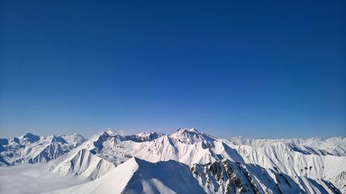 Scenic view of snowcapped mountains against clear blue sky