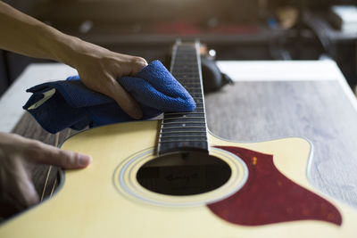 Close-up of person holding guitar on table