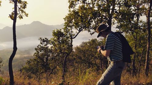 Side view of young man looking at trees