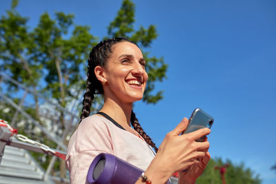 Man using smart phone against blue sky