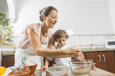 Boy assisting mother preparing food at home