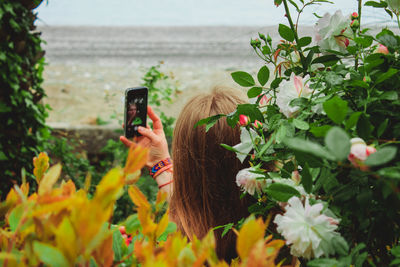 Close-up of woman photographing with mobile phone in sea