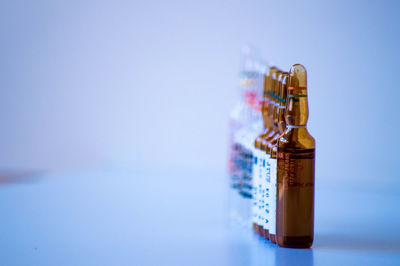 Close-up of glass bottle on table against blue background