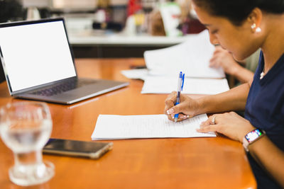 Woman filling document paper work with hand holding cell phone.