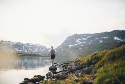 Woman standing at lake in mountains