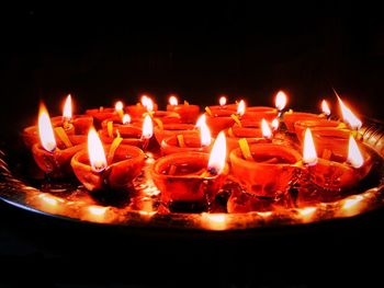 Close-up of lit candles burning in dark