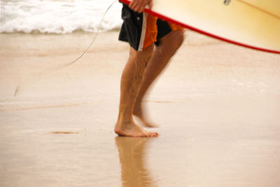 Low section of person on sand at beach