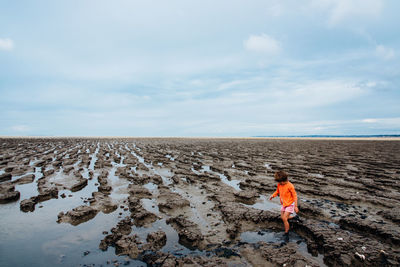 Full length of girl walking at beach against cloudy sky