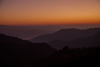 Scenic view of silhouette mountains against orange sky