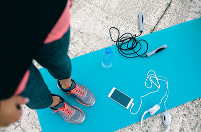 Low section of woman with objects standing on yoga mat