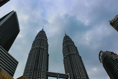 Low angle view of skyscrapers against cloudy sky