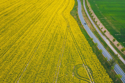 High angle view of an autonomous car driving next to a yellow field