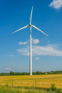 Wind turbines on field against sky