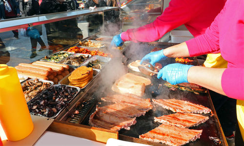 Cook with gloves while cooking sausages in the street food stall