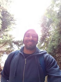 Portrait of young man standing against trees