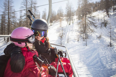 Happy mother and daughter traveling in ski lift