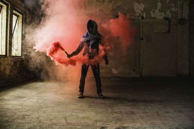 Full length of boy holding distress flare while standing against wall