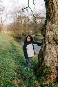 Portrait of young woman standing on tree trunk