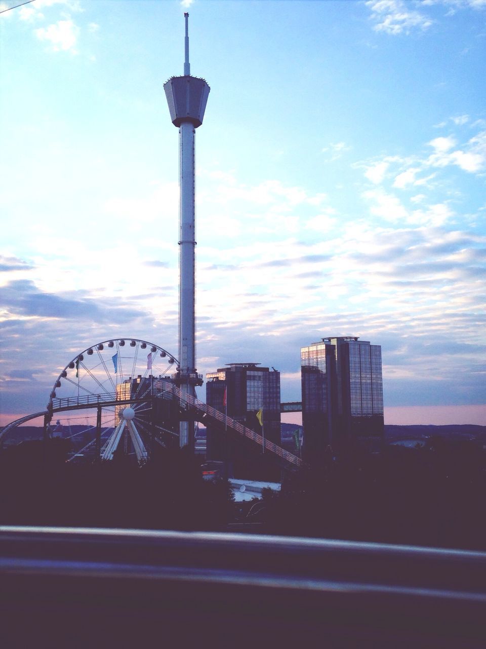 sky, architecture, built structure, building exterior, cloud - sky, city, tower, low angle view, transportation, cloud, ferris wheel, tall - high, blue, street light, travel destinations, amusement park ride, capital cities, outdoors, travel, no people