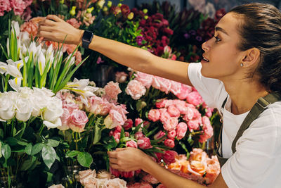 Side view of female florist arranging flowers in shop