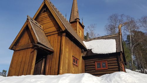 Low angle view of house on snow covered field against sky