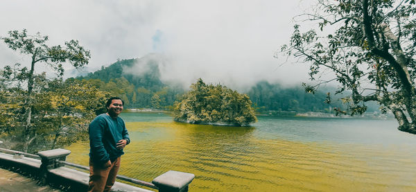 Man standing by lake against trees