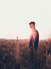 Young man standing on field against sky