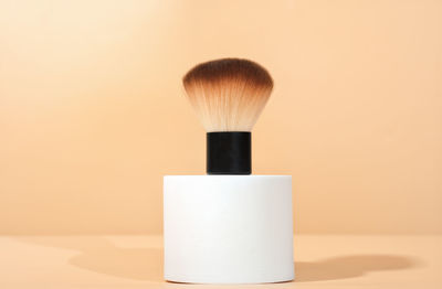 Cosmetic brush for powdred or blush application on white geometric podium. cosmetic accessories. 