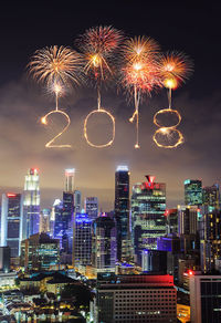 Firework display over illuminated buildings in city at night