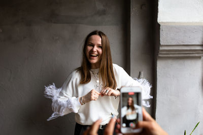 Two young women take photos and videos of each other on smartphone on a terrace