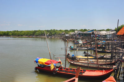 Boats moored in river by buildings against sky