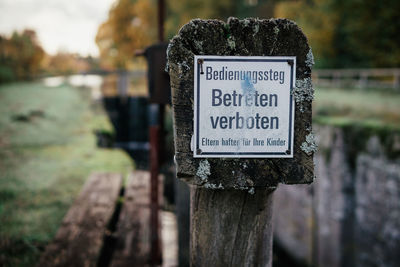 Close-up of information sign on wooden post