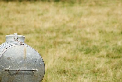 Close-up of old glass container on field