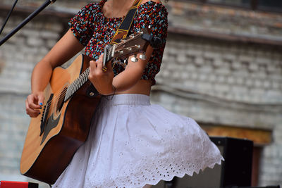 Midsection of woman playing guitar