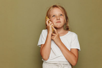 Portrait of young woman standing against wall