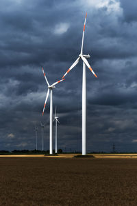 Windmills on field against sky