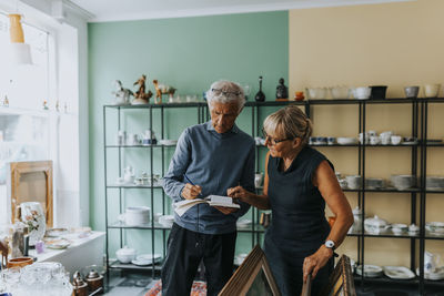 Female and male owners calculating while working in antique shop