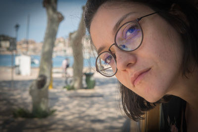 Close-up portrait of young woman wearing eyeglasses at beach