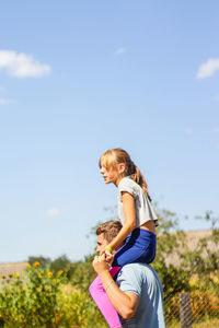 Side view of young woman standing against sky