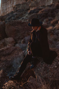 Side view of woman sitting on rock