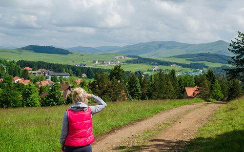 Blond woman watching and enjoying a mountain landscape in springtime